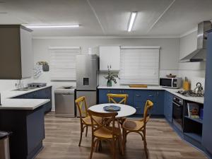 a kitchen with blue cabinets and a table and chairs at 1 On Wilderness in Klein-Brakrivier