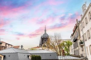 a building with a clock tower with a cloudy sky at Confort et Espace 12pers centre Lamartine in Clermont-Ferrand