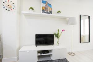 Biały salon z telewizorem i lustrem w obiekcie NEW AND COZY-STUDIO-CHUECA w Madrycie