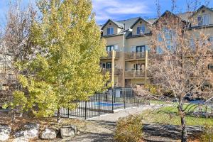 an apartment building with a fence and a tree at Eden Escape most desirable floor plans in all of Moose Hollow Luxury Condos in Eden
