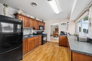 a kitchen with wooden cabinets and a black refrigerator at Poolside Palisade - A Fun Family Retreat for 6 in Marquette Heights