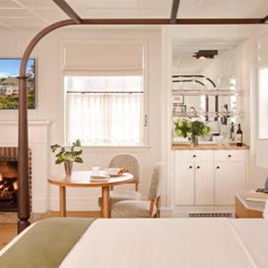 a room with a bed and a table and a kitchen at Canoe Place Inn & Cottages in Hampton Bays