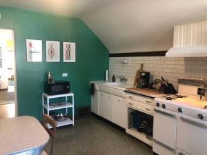 a kitchen with green walls and white cabinets and a stove at Gallery Loft of Oak Park #1 Top Host in IL in Oak Park