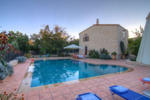 a swimming pool in front of a house at Allaria Villa Traditional Villa in Margarítai