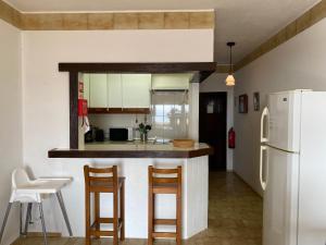 a kitchen with a counter with chairs and a refrigerator at Silver Moon Beach House in Lagos