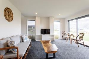 a living room with a couch and a tv and a table at Grand Peninsula Lodge in Wanaka