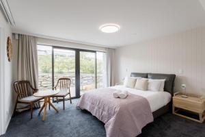a bedroom with a bed and a table and chairs at Grand Peninsula Lodge in Wanaka