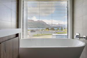 a bath tub in a bathroom with a large window at Grand Peninsula Lodge in Wanaka +52 photos