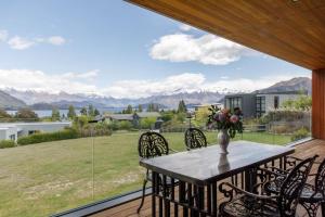 a table and chairs on a deck with a view of the mountains at Grand Peninsula Lodge in Wanaka