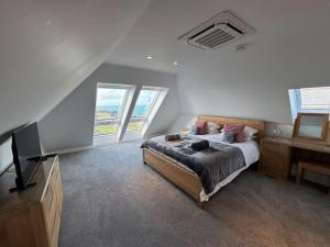 une chambre avec un lit, une télévision et des fenêtres dans l'établissement Camelot House 1 Bed Duplex Sea View Cabrio Balcony, à Tintagel
