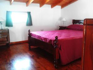 1 dormitorio con 1 cama con colcha roja en Cabañas Los Almendros en Merlo