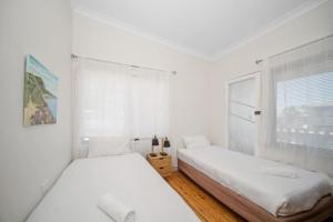 Manning PointにあるManning Point Heights Upstairsの窓のある白い部屋にベッドが2つある +5枚の写真