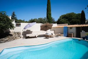 a pool with two umbrellas and a table and chairs at La Bastide Bleue La Ciotat in La Ciotat