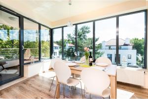 a dining room with a table and chairs and large windows at Baltica Heaven by 2HomeRent - przestronne apartamenty premium przy samej plaży in Rogowo