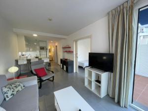 Una sala de estar con un sofá y un televisor de pantalla plana. en MONTE GOLF - TERRACE - POOLS - OCEAN VIEW - BEACH - WIFI - QUIET Complex, en Playa del Cura