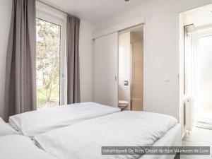 De CocksdorpにあるCozy Chalet Near North Seaの窓のある白い部屋にベッドが2つある