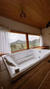 a bath tub in a room with a window at Vilare's da Mantiqueira in Queimada