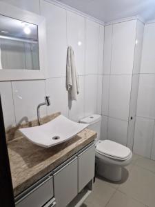 une salle de bain blanche avec un lavabo et des toilettes dans l'établissement Casa aconchego!, à Gramado 6 autres photos