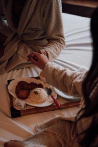 a person sitting on a bed with a plate of food at Motel Desejo Mossoró in Mossoró +9 photos
