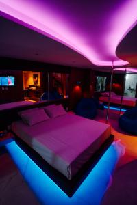 a bedroom with a bed with purple and blue lights at Motel Desejo Mossoró in Mossoró