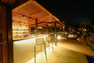 a bar with stools on a patio at night at Hotel Experience João Fernandes in Búzios