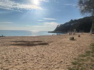 a beach with people and the ocean on a sunny day at Canyelles BBQ Apartment in Lloret de Mar