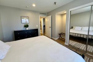 a bedroom with a large white bed and a mirror at Aksarben View Gem-Near UNO in Omaha +4 photos