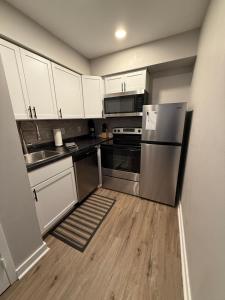 a kitchen with white cabinets and a stainless steel refrigerator at Aksarben View Gem-Near UNO in Omaha