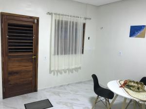 a room with a table and chairs and a door at Flat com quarto e sala in Viçosa do Ceará