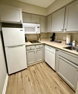 Una cocina con gabinetes blancos y un refrigerador blanco. en Cozy Aksarben Living-close to I-80 & WFH desk, en Omaha