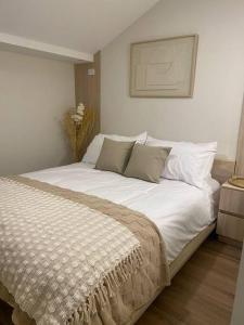 a bedroom with a large bed with white sheets and pillows at Apartamento con encanto cerca del centro de Cuenca in Cuenca