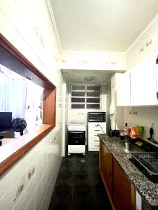 a kitchen with white cabinets and a black floor at Apartamento 412B com varanda e vista in Santos