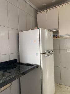 - un réfrigérateur blanc dans une cuisine avec des placards blancs dans l'établissement Casa na praia no Guarujá, à Guarujá