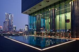 a building with a swimming pool in front of a city at Hotel ICON in Hong Kong