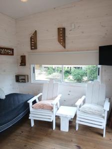 two white chairs and a bed in a room at Nio de Baixo in La Pedrera +74 photos