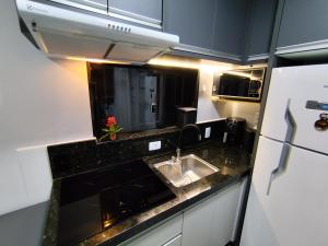 eine kleine Küche mit Spüle und Kühlschrank in der Unterkunft Casa de praia - Bombinhas in Bombinhas