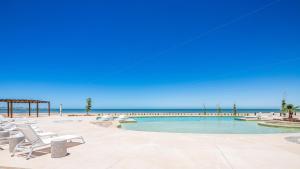 a swimming pool with chairs and the beach at Costa Divina A2 by Kivoya in La Choya