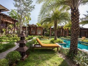 a resort yard with a bench and a swimming pool at The Cottage Aonang in Ao Nang Beach