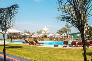 a pool with chairs and umbrellas in a resort at Hotel Resort Thiago in Chincha Alta