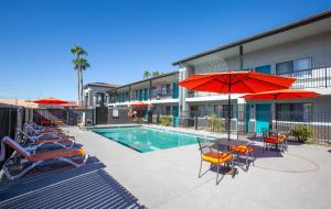 a pool with chairs and umbrellas next to a building at The Hotel Serene Glendale Peoria, Surestay Collection by Best Western in Glendale