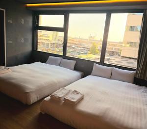 two beds in a room with a large window at ピンポンホテル&キャビン pin pon hotel & cabin in Shunan