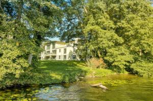 une maison au bord d'une rivière avec des arbres dans l'établissement Apartment Erkenntnis am See mit Sauna und Kamin, à Krakow am See