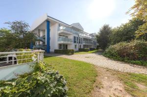 a large white building with blue columns and a fence at Seestern - Charmante 2-Zimmer-Wohnung mit Balkon in Zingst +18 photos