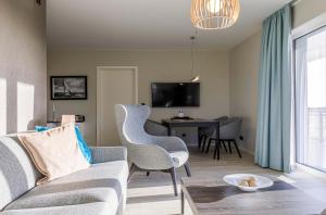 een woonkamer met een bank, stoelen en een tafel bij 5 Sterne Ferienwohnung Strandblick in Wustrow +20 foto's