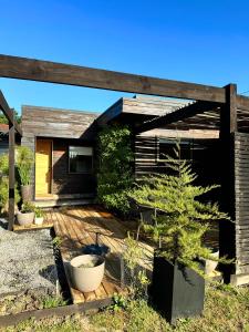 a house with a wooden deck with a pine tree at Cabaña Luna de Lobos in Pichilemu