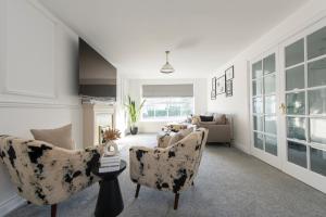 ein Wohnzimmer mit zwei Stühlen und einer Couch in der Unterkunft Stunning 5 bedroom detached house in Hornchurch in Romford