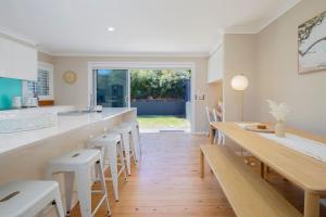 a kitchen with a long bar with stools at Aurora Grove - A Familly Retreat at Caves Beach in Caves Beach