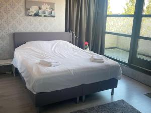 a bedroom with a bed with white sheets and a window at Alkmaar aan het Water in Alkmaar