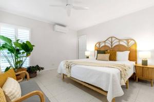 a bedroom with a large bed with a wooden headboard at Cedar Villa - A Designer Pool House by the Beach in Palm Cove +34 photos