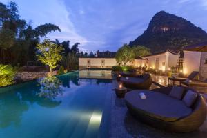a swimming pool with two lounges and chairs around it at Banyan Tree Yangshuo in Yangshuo
